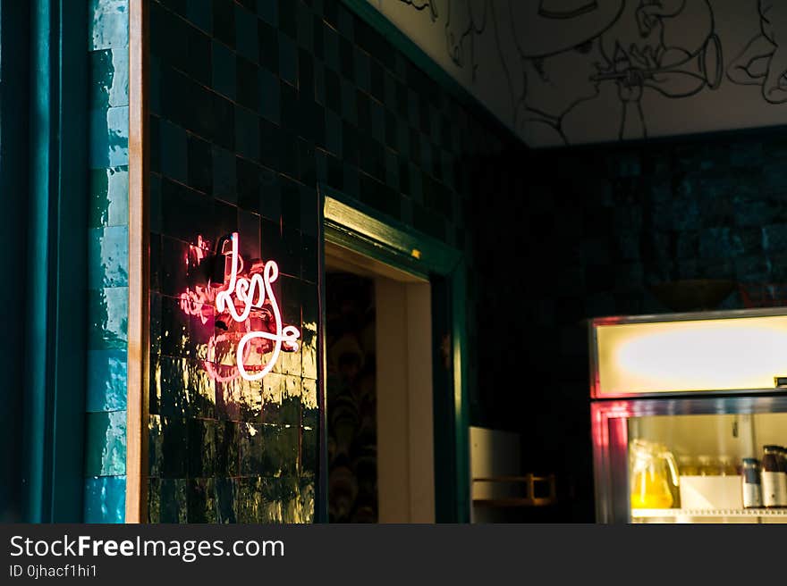 Less Neon Sign Mounted on Glass Board Near Open Window and Glass Display Rack