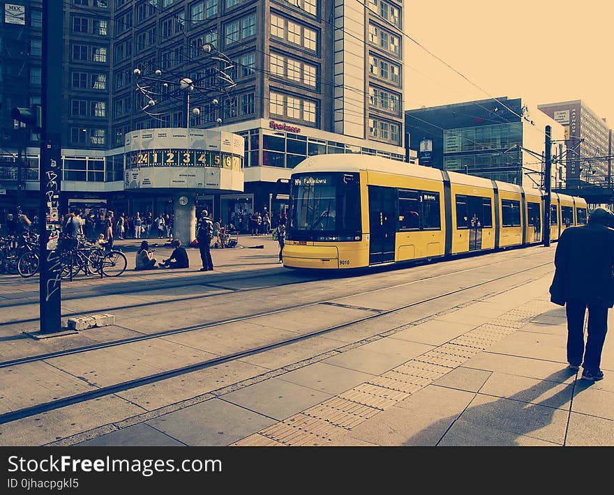 Selective Color Photography of Yellow Train Near Concrete Buildings