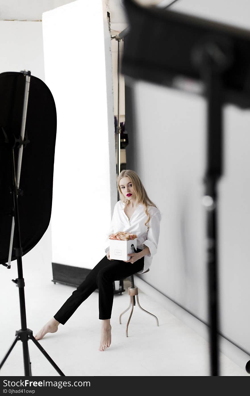 Woman Sitting on Stool While Holding Box