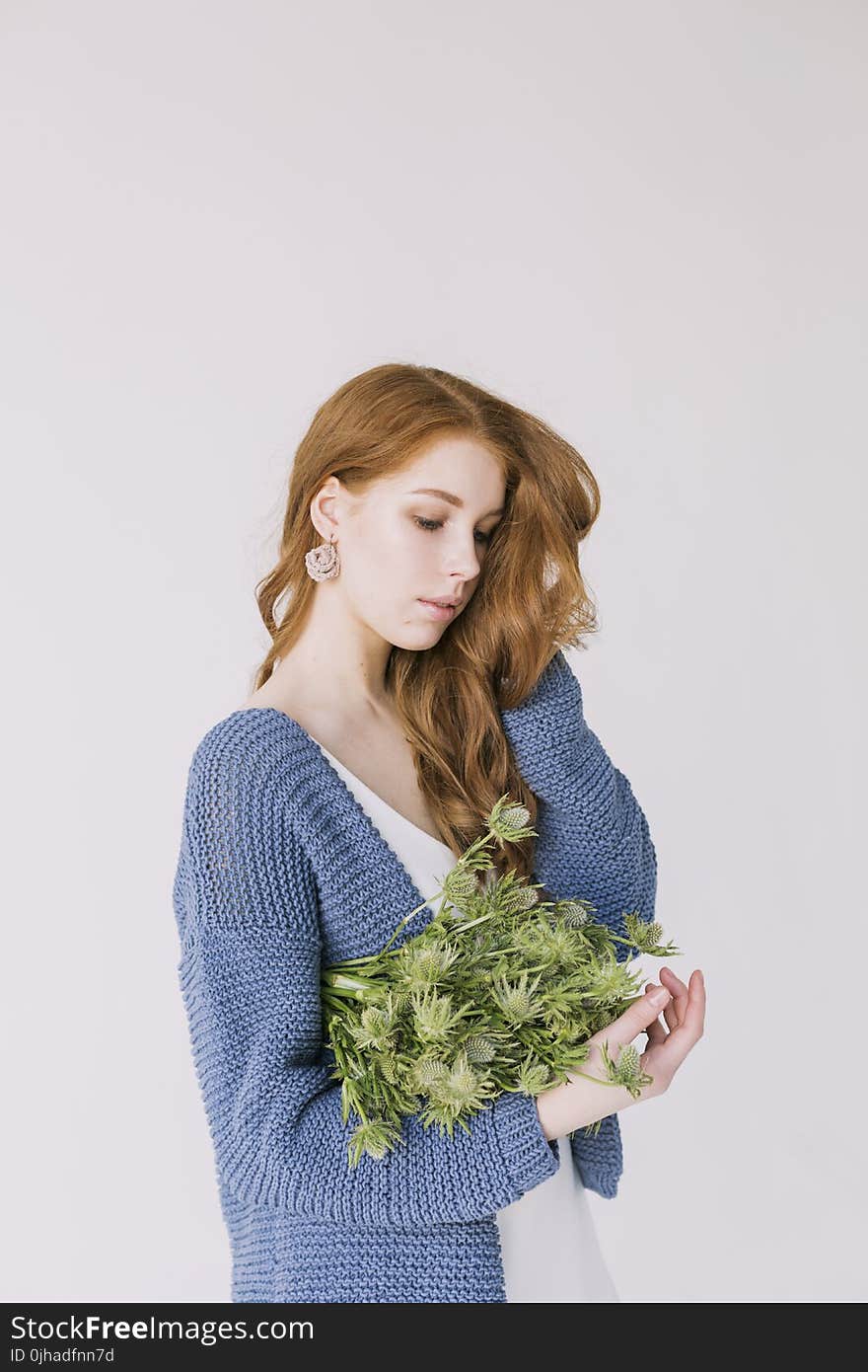 Woman in Blue Cardigan Holding Green Flowers