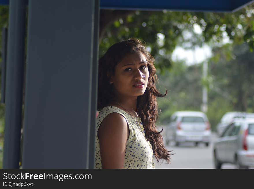 Photo of Woman in White Blouse Leaning on Gray Steel Shed