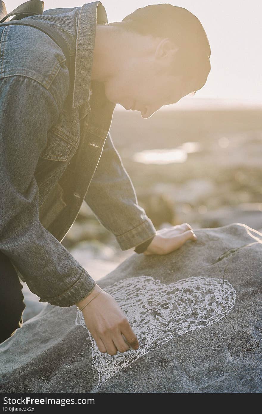 Man Sketching Heart on a Gray Rock