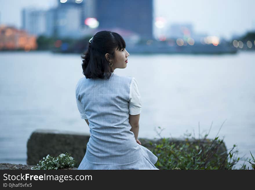 Photography of Woman Sitting Beside Body of Water