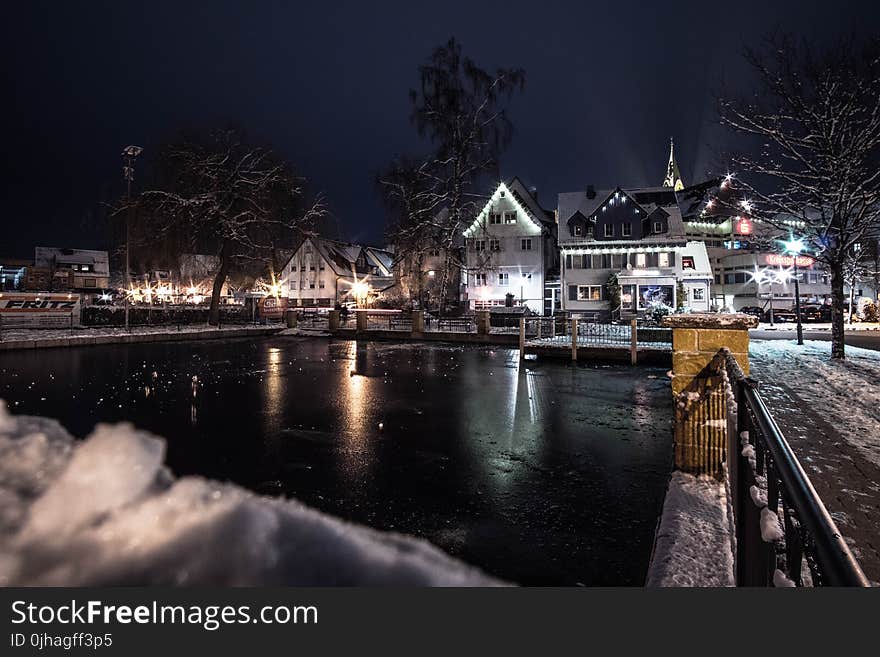 Body of Water Infront of White 3-storey Houses during Night Time