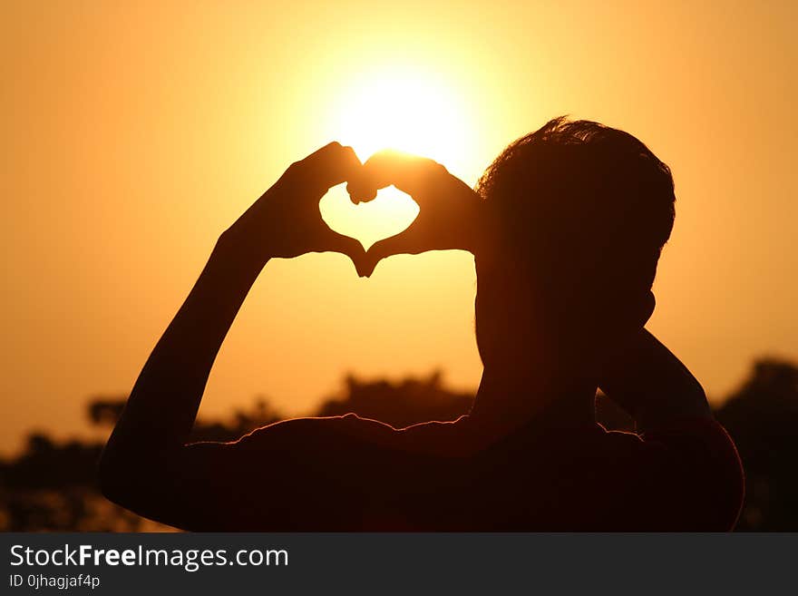 Silhouette Photo of Man Doing Heart Sign during Golden Hour