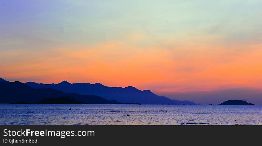 Silhouette of Mountain Beside Ocean during Orange Sunset