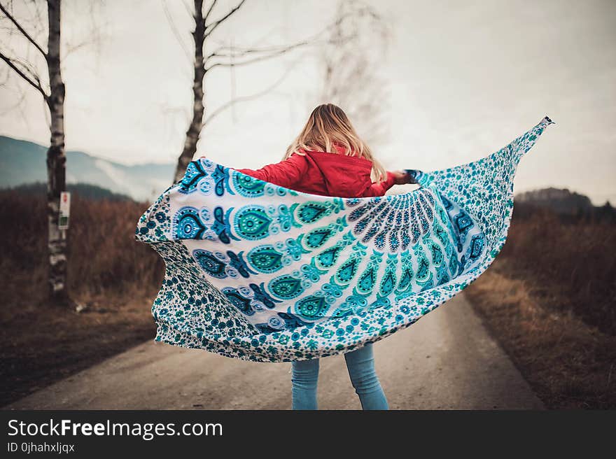 Woman Standing on the Middle of the Road Holding Blanket