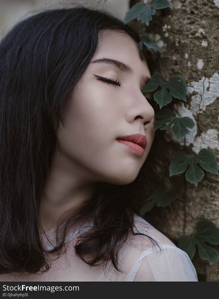 Woman Closing Her Eyes Beside Green Vine Plant