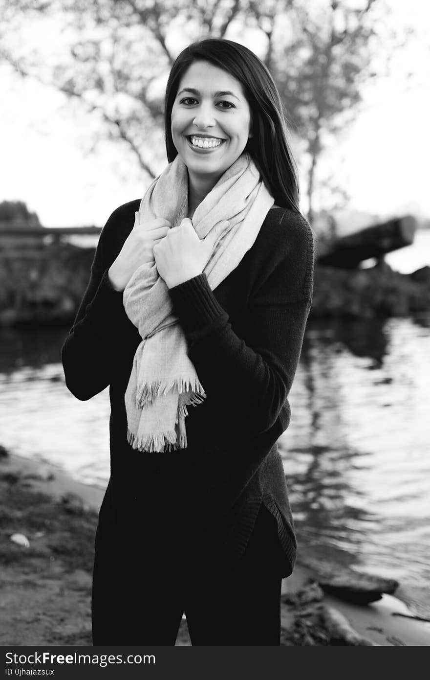 Grayscale Photography of a Woman Wearing Sweatshirt and Black Pants While Holding Scarf