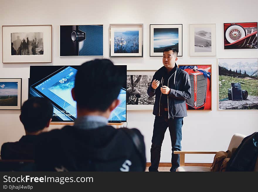 Man Beside Flat Screen Television With Photos Background