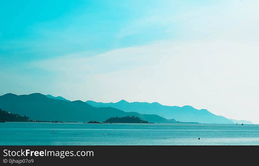 Silhouette of Mountain Near the Body of Water Photo in Daytime