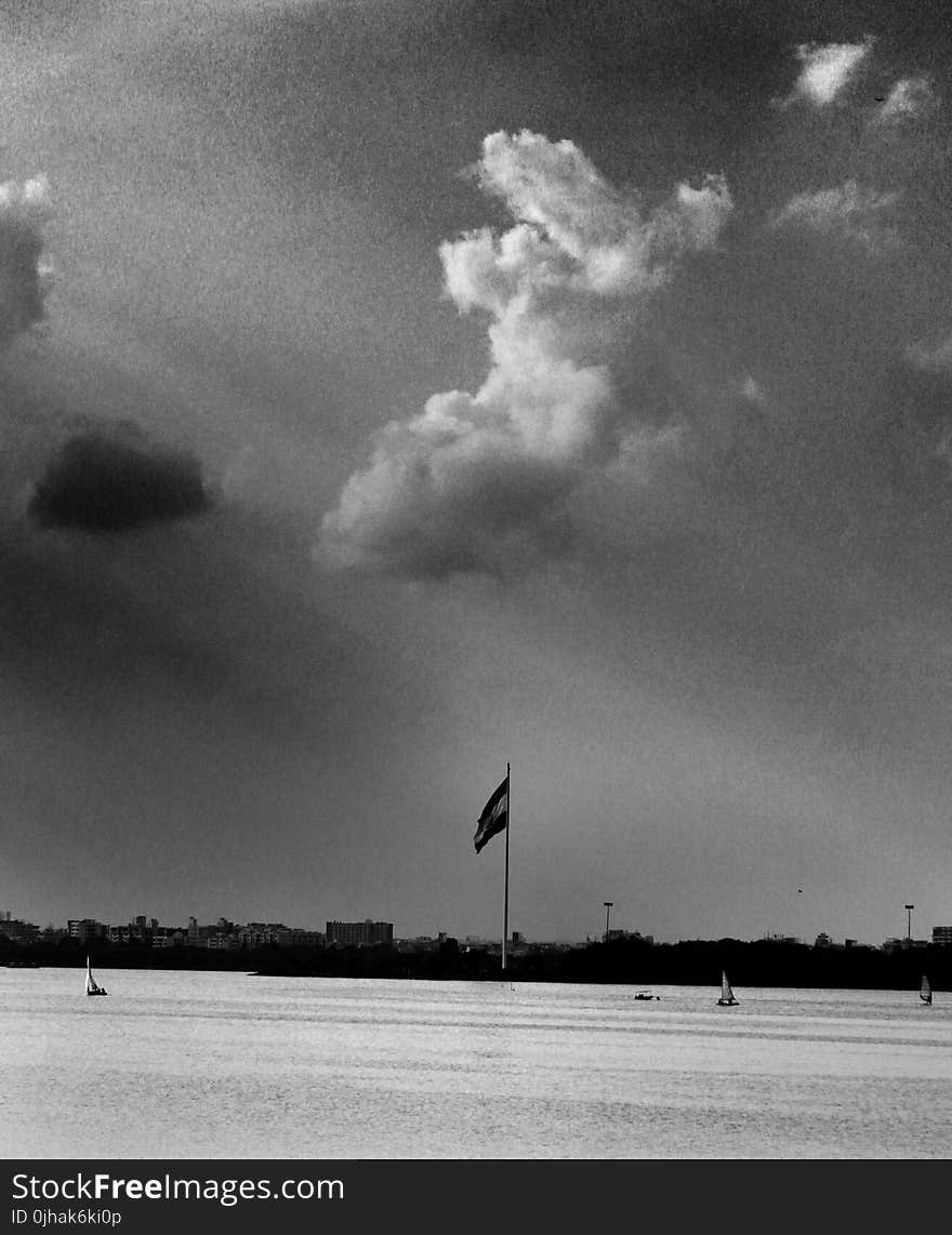 Grayscale Photo of Flag and Clouds