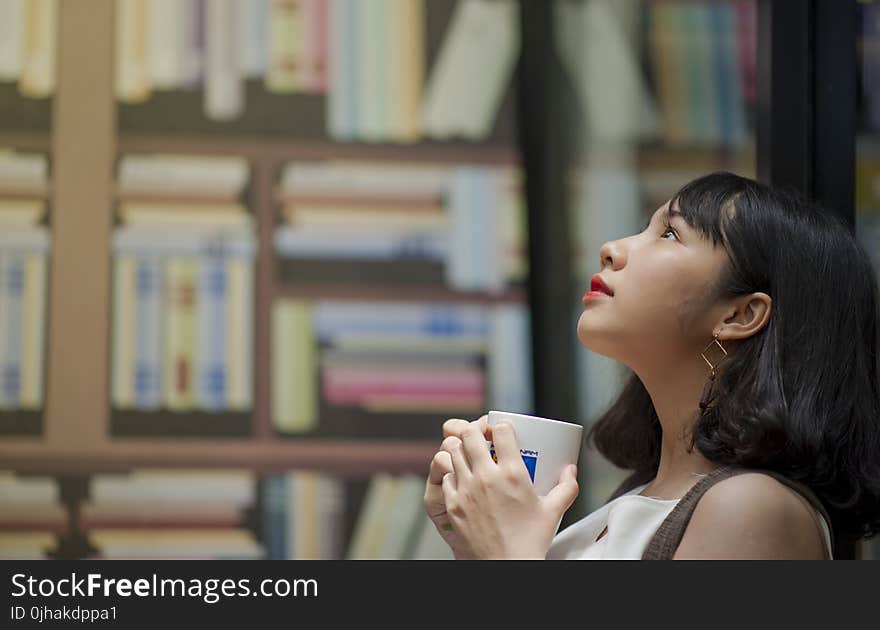 Woman Wearing White Shirt Looking on Top Holding White Ceramic Mug