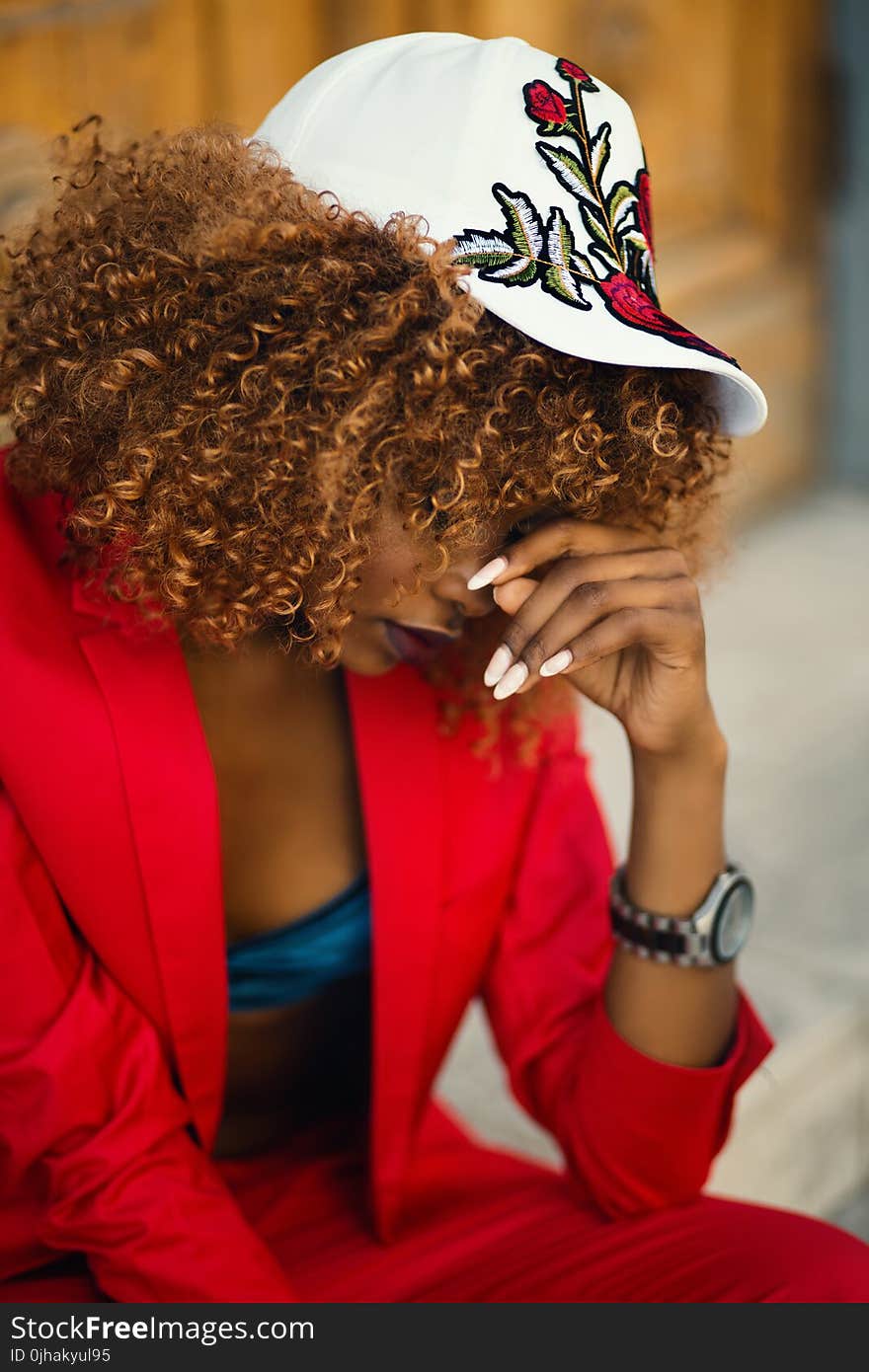 Woman in Red Suit Jacket Sitting Near Brown Surface