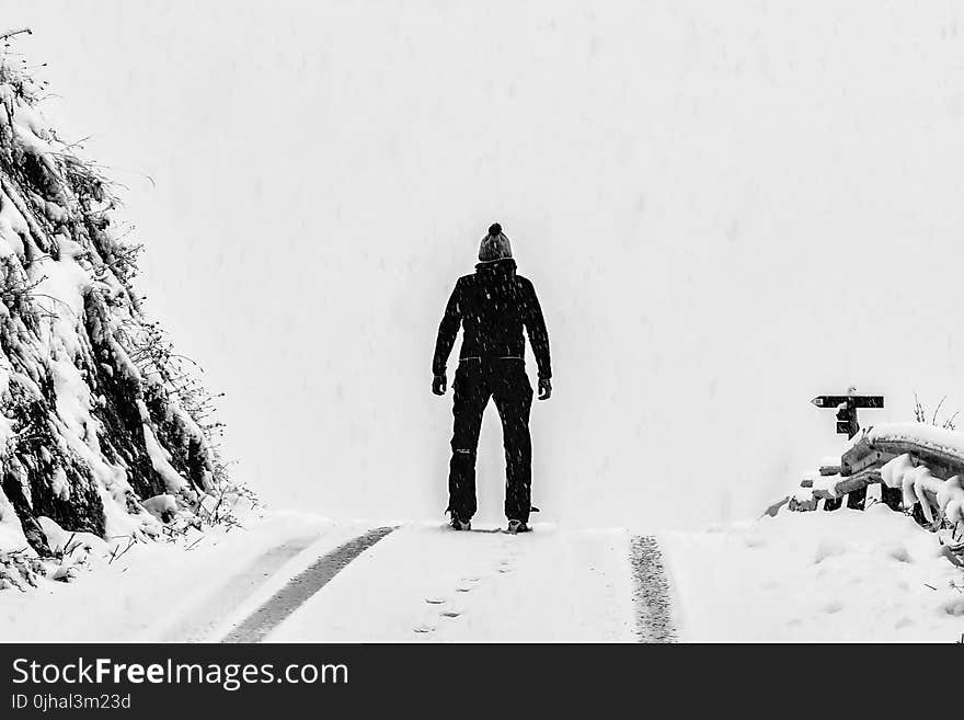 Man Standing on White Snow Covered Ground Beside Mountain