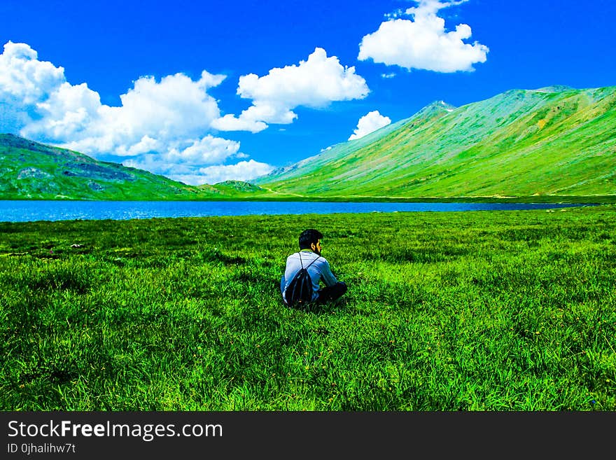 Boy Sitting on Green Grass Field