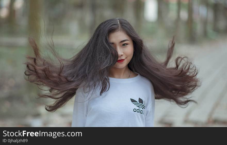 Woman With Long Hair Waving on Air and Wearing White Adidas Shirt