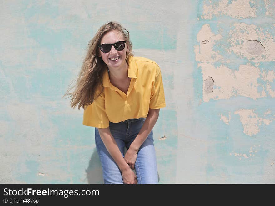 Woman Wearing Yellow Polo Shirt Standing in Front of Teal Concrete Wall