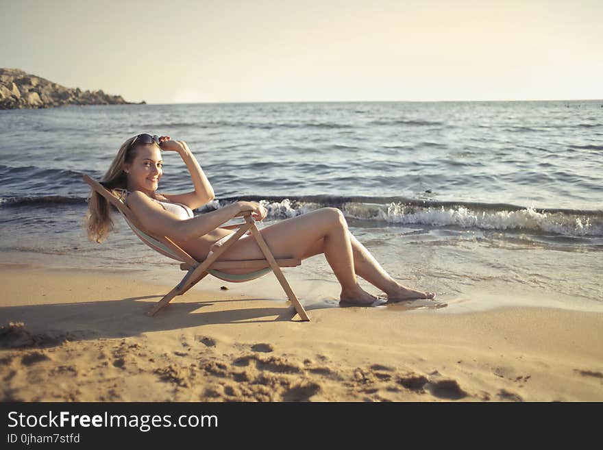 Woman Sitting on Sun Chair Beside Seashore at Daylight Photography