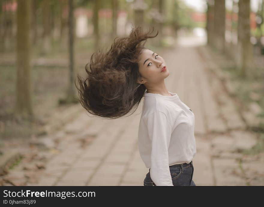 Closeup Photo of Woman in White Crew-neck Long-sleeved Shirt Shaking Her Hair in the Middle on Road