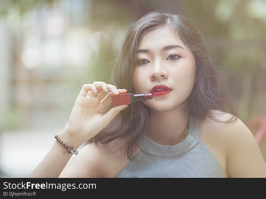 Woman Wearing Gray Halter-neckline Top Holding Red Lipstick