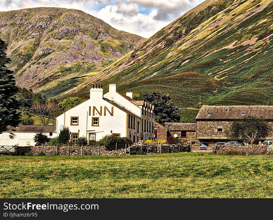 White Concrete Inn Near Green Covered Mountain at Daytime