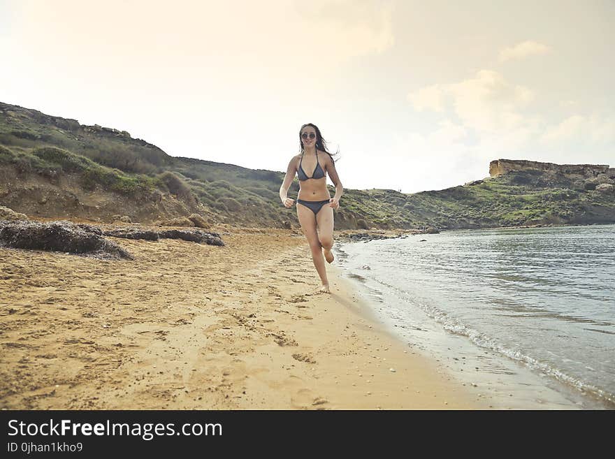 Woman Wearing Grey Bikini Running On White Sand Seashore