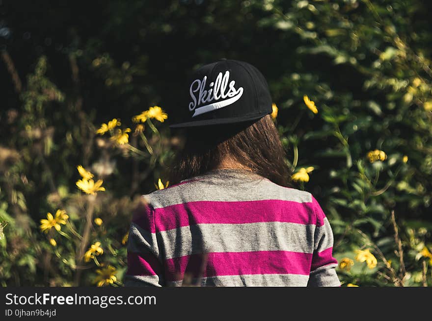 Woman in Gray and Pink Longsleeve Shirt Wearing Black Skill Printed Cap