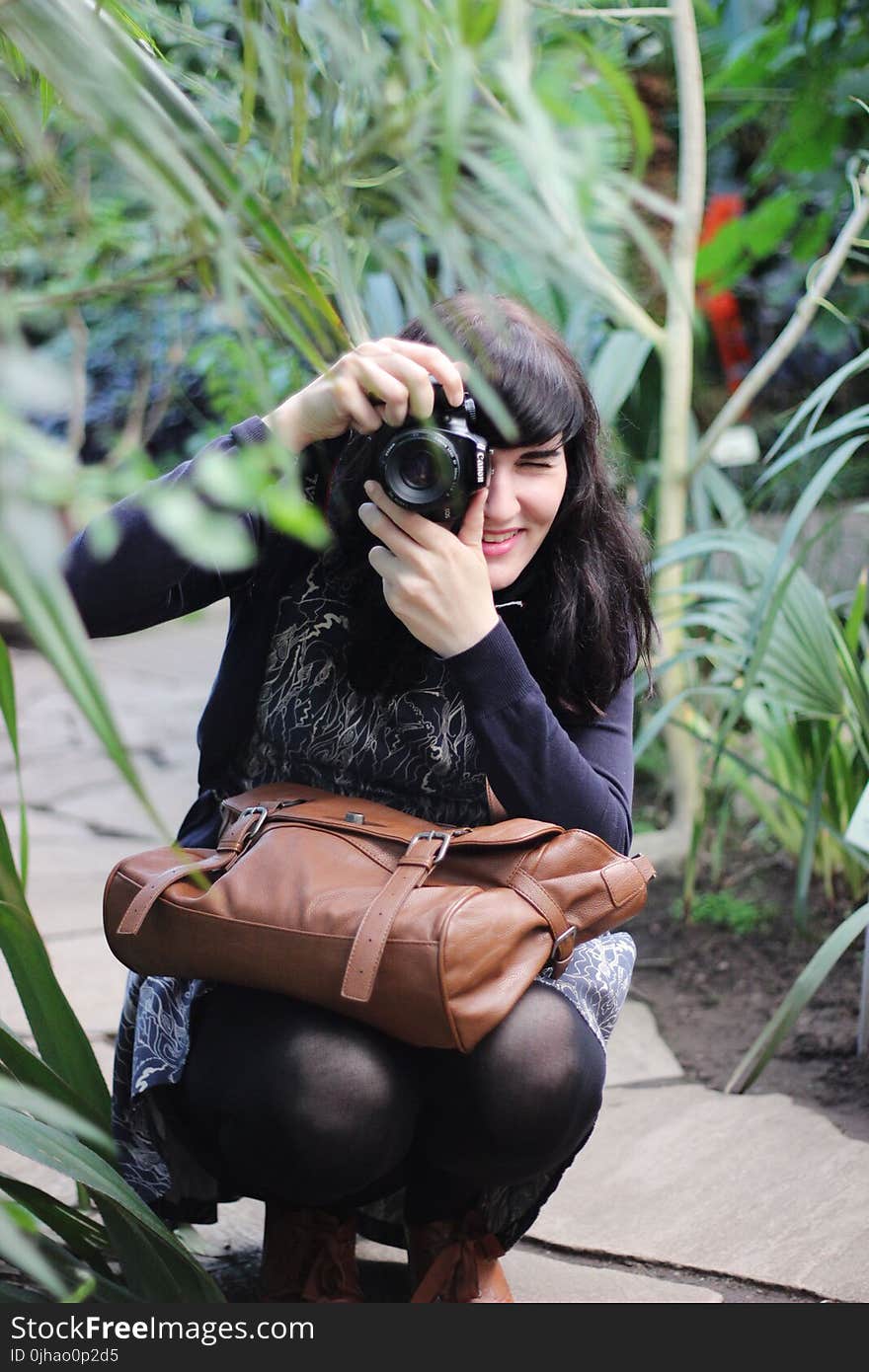 Woman Taking Picture While Holding Brown Leather Bag