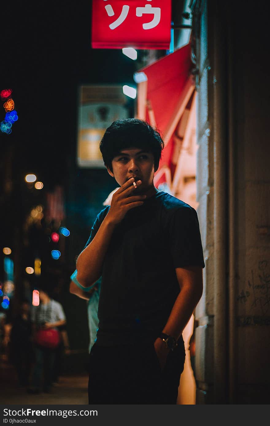 Man Wearing Black Crew-neck Shirt Holding White Cigarette during Night Time