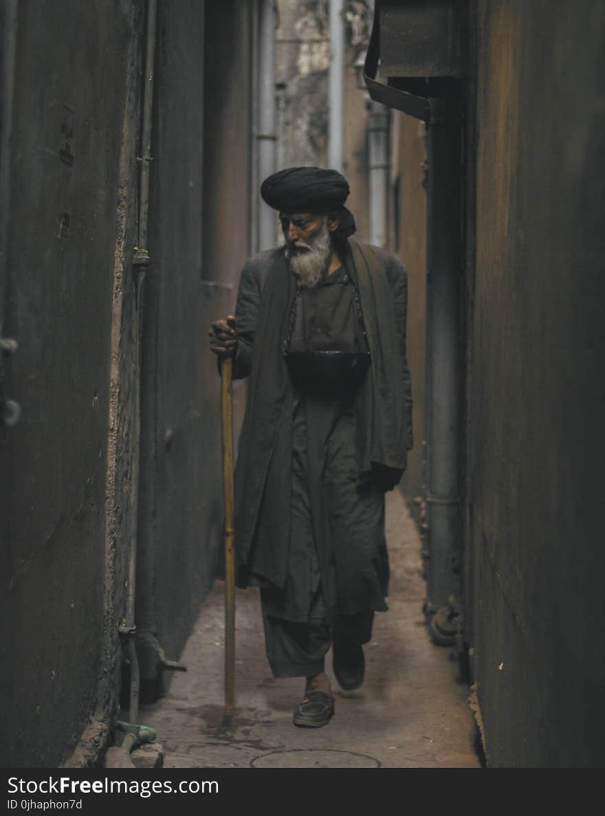 Photo of an Old Man Walking in the Alley