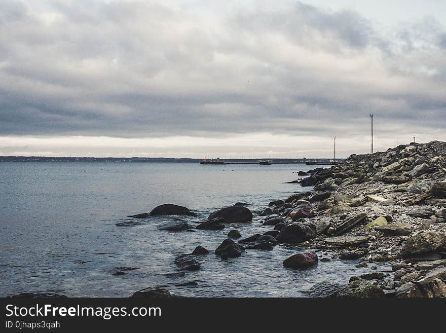 Rocks Beneath the Sea Under Cloudy Sky