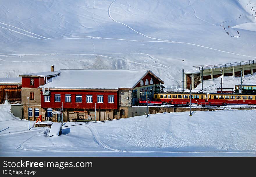 Yellow and Red Train Beside Snowy Mountain