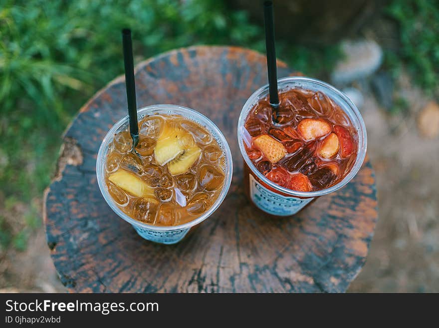 Selective Focus Photo of Two Juice Filled Plastic Cups