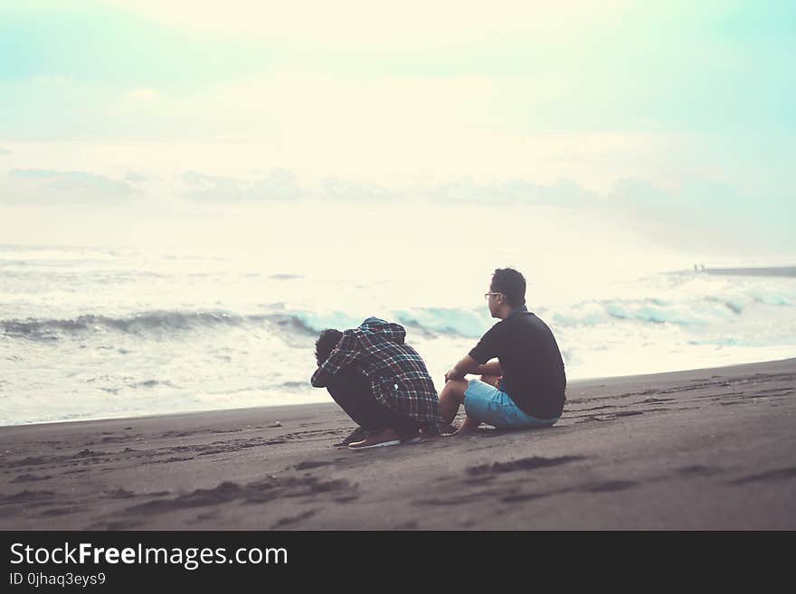 Two Man Sitting on the Sand Near the Beach