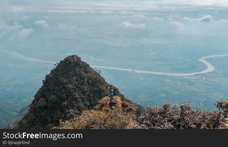 Man in Blue on Top of the Mountain With Areal View