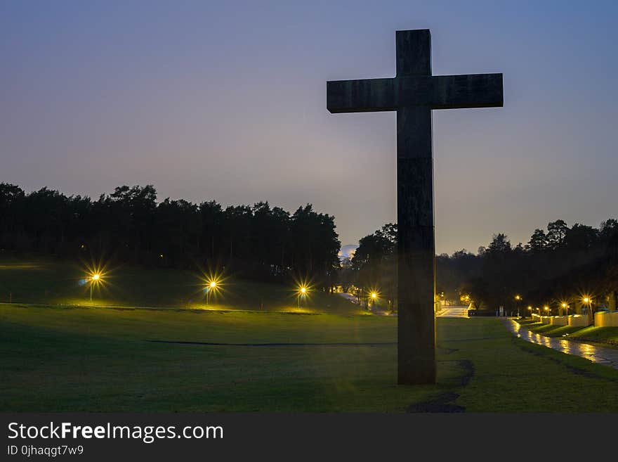 Brown Cross Statue on Green Grass Field With Turned on Light during Nighttime