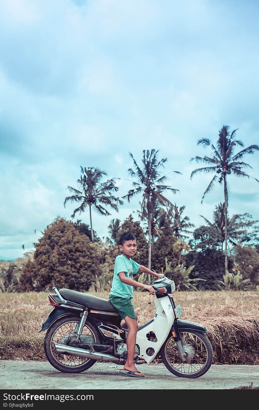 Boy Riding on White and Red Underbone Motorcycle