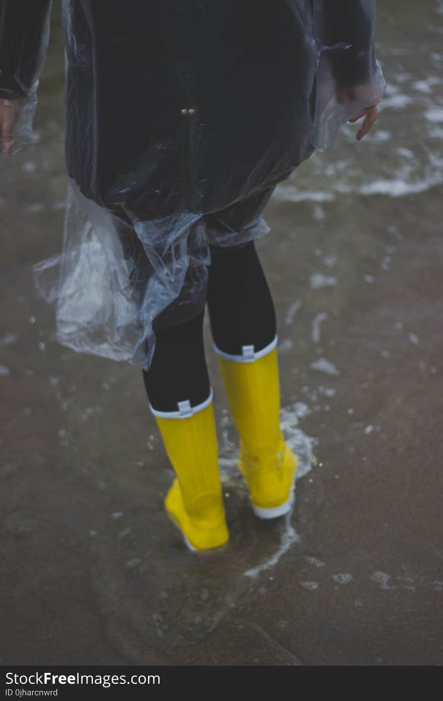 Person Wearing Clear Plastic Raincoat and Pair of Yellow Rainboots