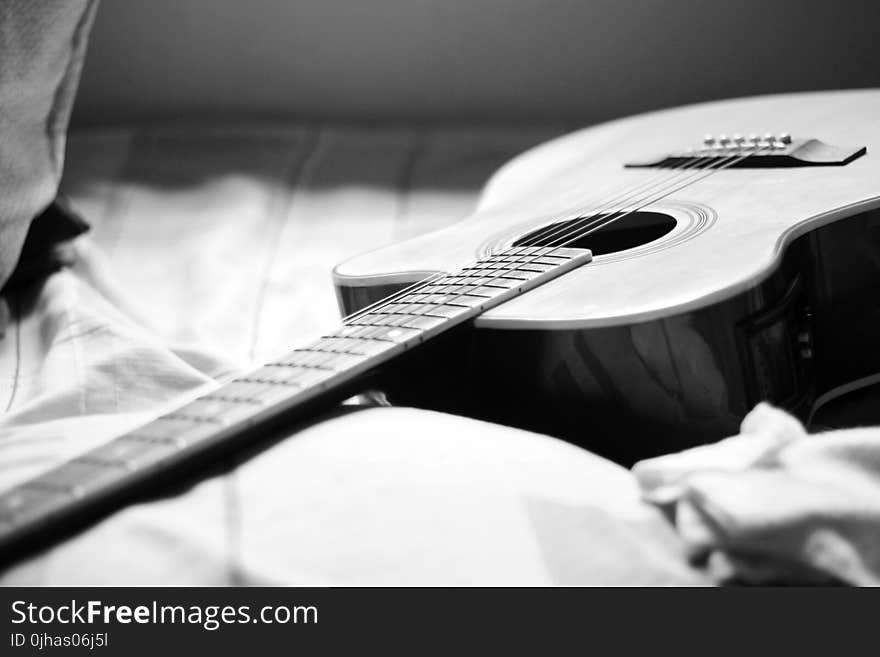 Gray Scale Photography of Acoustic Guitar on Bed