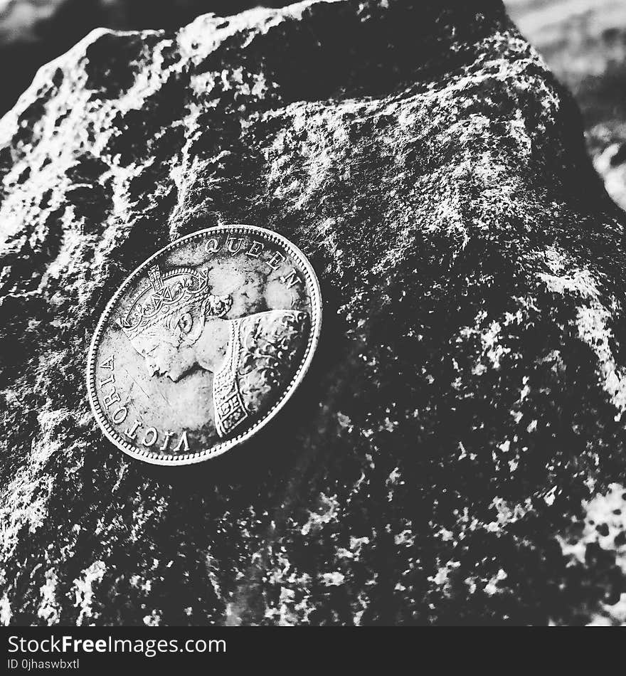 Grayscale Photo of Victoria Queen Coin on Top of Rock