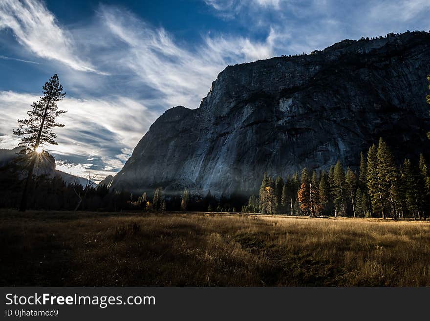 Photo of Mountain and Trees Under Cloudy Skies