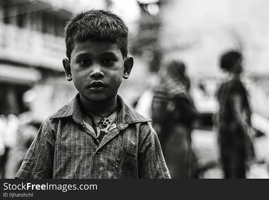 Boy in Collared Button-up Shirt Standing Near Two Person Walking