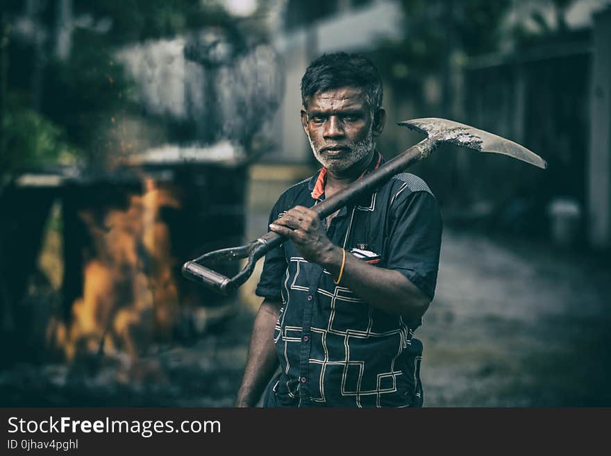 Depth of Field Photography of Man in Black Shirt Holding Shovel