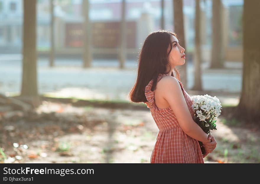 Woman Wearing Brown Sleeveless Dress Carrying White Flower Bouquet