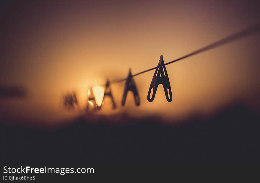 Shallow Focus Photography of Wooden Clothes Clip on Clothes String Rack