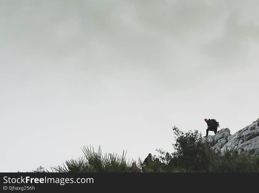 Person on Rocky Mountain Under White Cloudy Sky