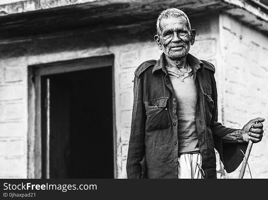 Man Wearing Button-up Shirt Standing Near Concrete House Greyscale Photo