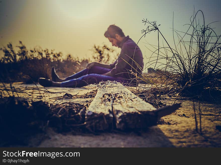 Man Sitting Near Brown Wood Plank