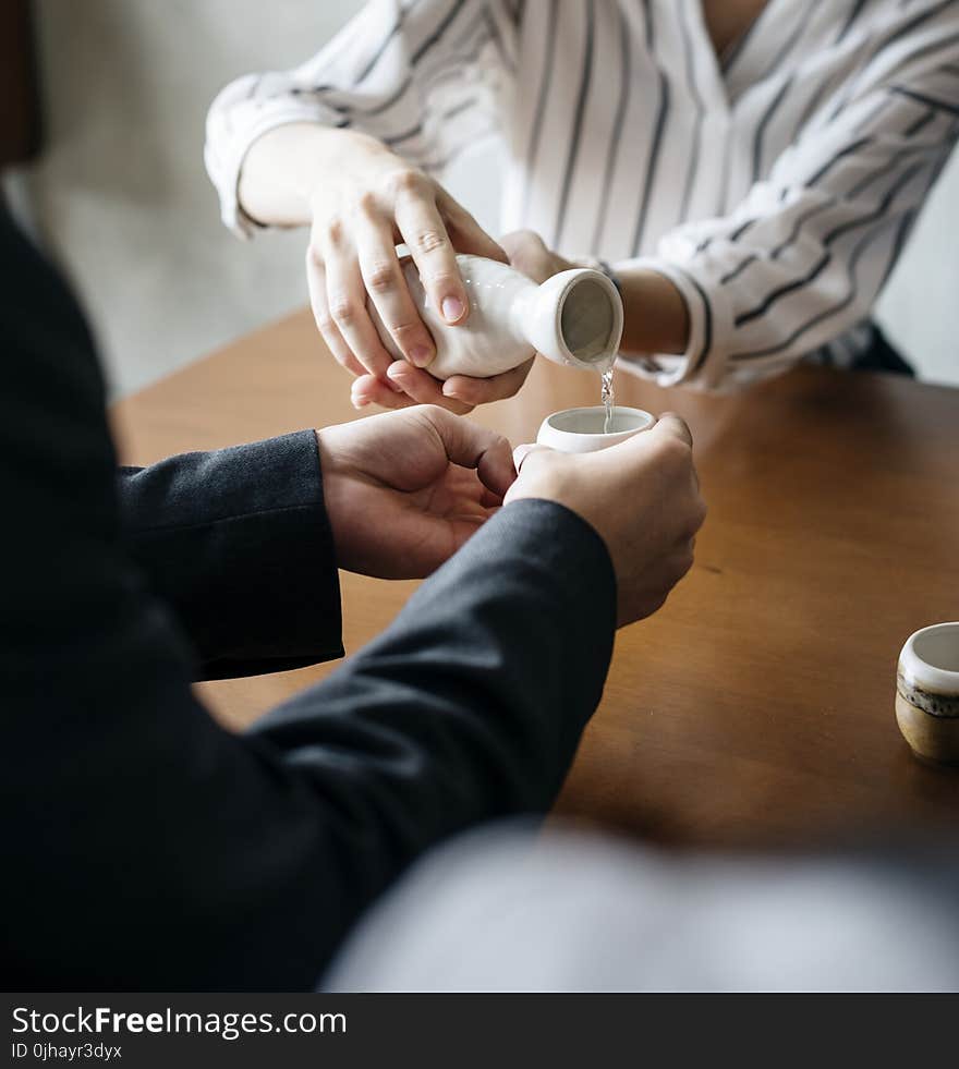 Person Pouring Liquid to Another Persons Cup